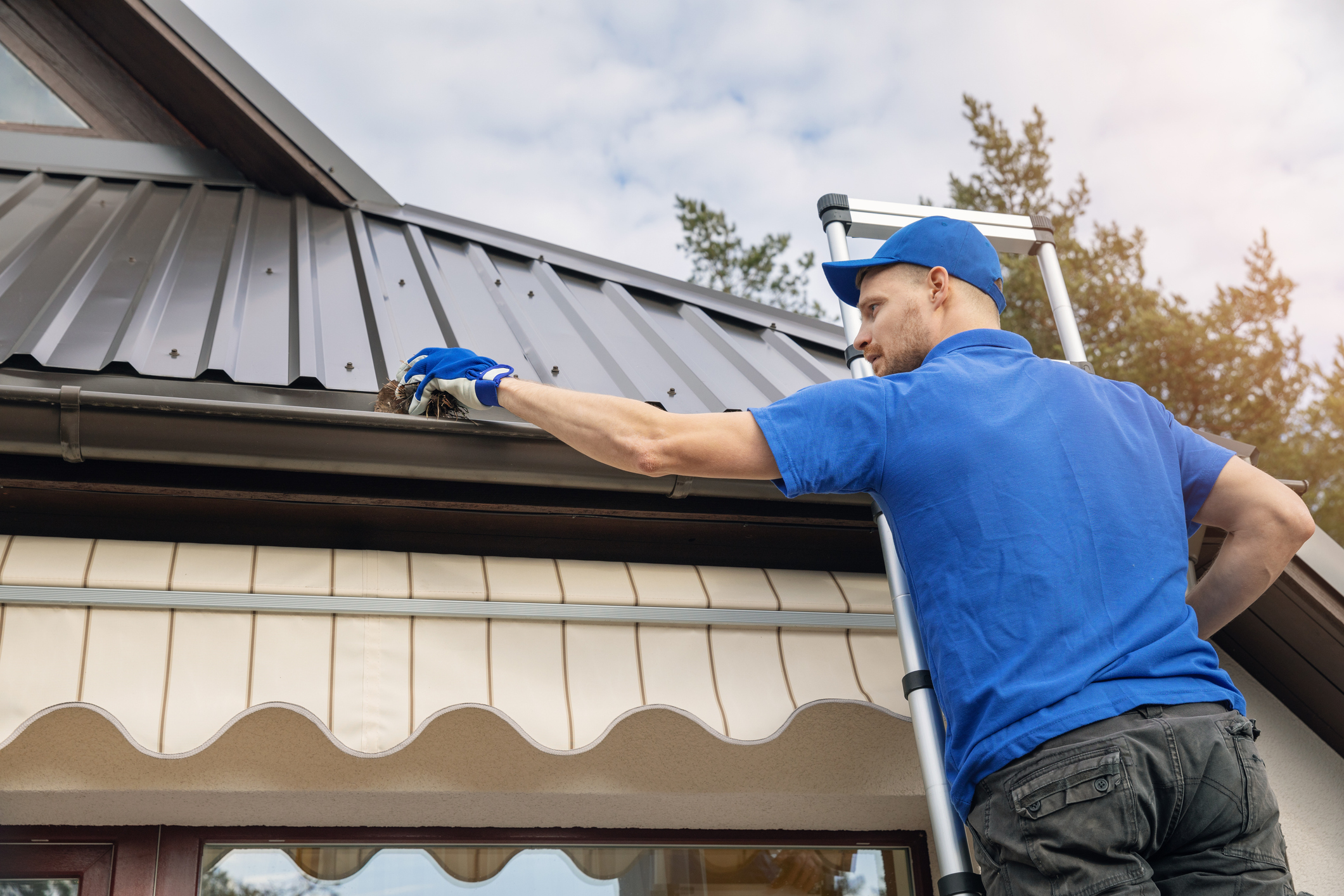 man standing on ladder and cleaning roof rain gutter from dirt man standing on ladder and cleaning roof rain gutter from dirt